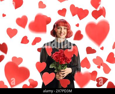 Eine junge Frau, die einen Haufen roter Rosen unter dem Regen von Herzen hält, isoliert auf weißem Hintergrund Stockfoto