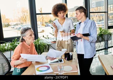 Eine vielfältige Gruppe von hart arbeitenden, hübschen Geschäftsfrauen versammelt sich an einem Tisch, um in einem Büro eine gemeinsame Diskussion zu führen. Stockfoto