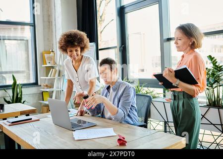 Eine Gruppe von Geschäftsfrauen versammelte sich um einen Tisch und konzentrierte sich auf einen Laptop-Bildschirm. Stockfoto