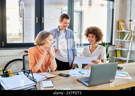 Fleißige Geschäftsfrauen, vielfältig und inklusiv, versammeln sich an einem Holztisch in einem Büro, um zusammenzuarbeiten. Stockfoto