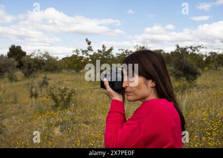 Milde erwachsene Frau, die eine Reflexkamera benutzt, um Fotos zu machen. Hobbys. Foto Stockfoto