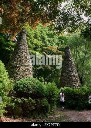 Frau, Wandern auf einem Waldweg und durch zwei Steintürme, Pagode Stockfoto