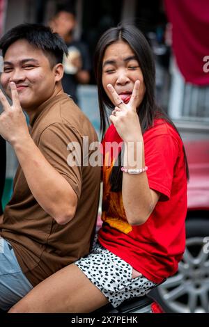 Ein junges philippinisches Paar rastet auf einem Roller vorbei und macht lustige Handsignale im Tondo District Manila auf den Philippinen. Stockfoto