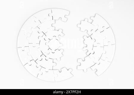 Nahansicht eines leeren, kreisförmigen Puzzles von oben, das in zwei Teile auf weißem Hintergrund aufgeteilt ist. Stockfoto