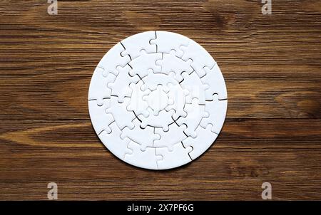 Rundes Puzzle-Set auf hölzernem Hintergrund. Zeit- und Problemlösungskonzept. Stockfoto