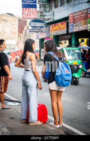 Zwei junge philippinische Freundinnen warten auf einen Bus oder Jeepney im Tondo District Manila auf den Philippinen. Stockfoto