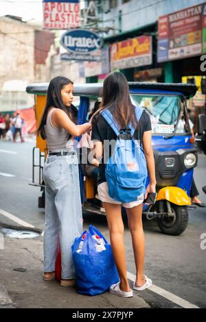 Zwei junge philippinische Freundinnen warten auf einen Bus oder Jeepney im Tondo District Manila auf den Philippinen. Stockfoto