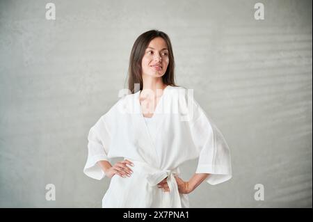 Studio-Porträt der schönen glücklichen Frau in weißer Kleidung vor der Thai-Massage. Stockfoto