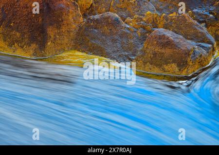 Intime Landschaft mit mineralreichen Felsen in Rio Tinto mit warmen Tönen im Kontrast zum kühl weißen Gleichgewicht des fließenden Wassers. Stockfoto