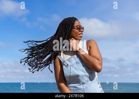 Eine Frau genießt einen sonnigen Sommertag an der Küste Barcelonas mit luftigem Meer im Hintergrund Stockfoto