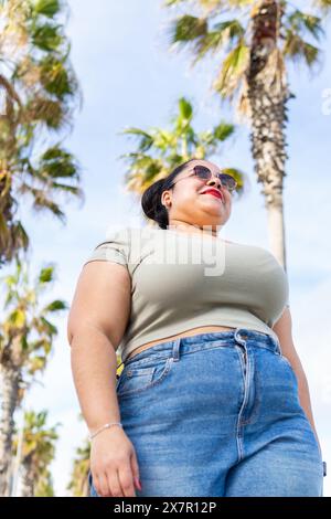 Eine selbstbewusste Frau genießt einen sonnigen Tag inmitten von Palmen in Barcelona, der im Sommer Stil liegt Stockfoto