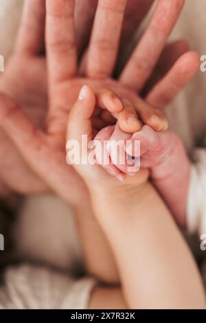 Eine sanfte und herzerwärmende Nahaufnahme der Hand eines Babys, die einen erwachsenen Finger umklammert, symbolisiert Liebe, Vertrauen und die Eltern-Kind-Bindung Stockfoto