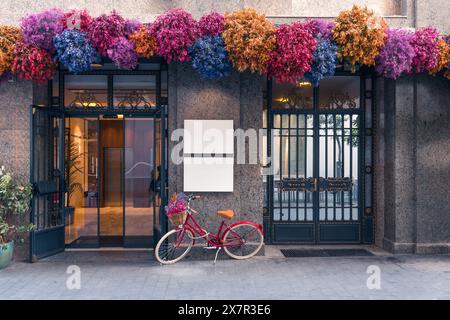 Bezaubernder Eingang eines Gebäudes in Madrid mit farbenfrohen Blumendekorationen und einem roten Fahrrad Stockfoto