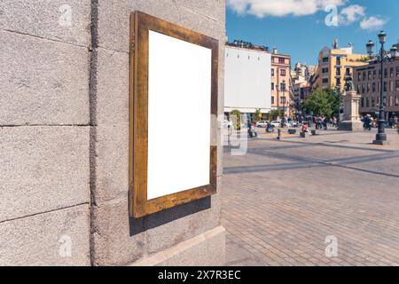 Ein leerer Plakatrahmen, der an einer historischen Steinmauer auf einem pulsierenden Platz in Madrid befestigt ist und auf Ihre Werbung oder Nachricht wartet Stockfoto