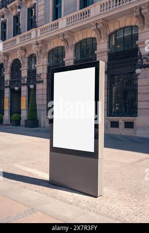 Ein vertikales Modell einer leeren Werbetafel an einem sonnigen Tag mit der kunstvollen Architektur Madrids im Hintergrund Stockfoto