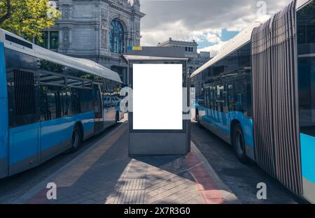 Leere Werbetafeln an einer Bushaltestelle in Madrid City, mit blauem Bus und historischem Gebäude im Hintergrund Stockfoto