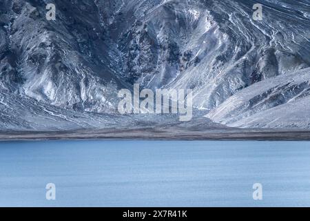 Majestätische Berge mit komplizierten Texturen ragen über der ruhigen Oberfläche eines Hochlandsees in Island hervor, die eine ruhige und wilde Landschaft darstellen. Stockfoto