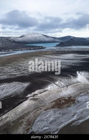 Aus der Vogelperspektive wird die ruhige Schönheit des schneebedeckten Hochlands mit kontrastierenden Schichten aus dunklem vulkanischem Sand und Eis veranschaulicht Stockfoto