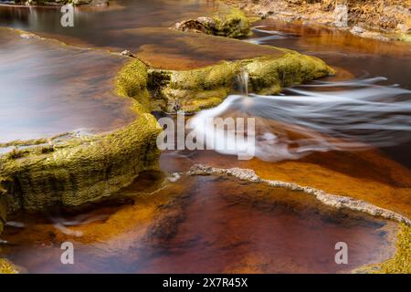 Das Bild zeigt moosige Felsen und glattes, kaskadierendes Wasser des Riotinto River Stockfoto