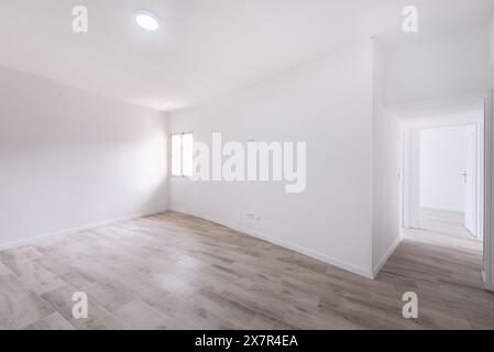 Dieses Bild zeigt das Innere einer leeren Wohnung, beleuchtet durch natürliches Tageslicht von einem Fenster. Es bietet ein minimalistisches Raumdesign mit weiß Stockfoto