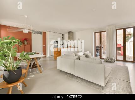 Dieses Foto zeigt ein geräumiges, modernes Wohnzimmer, das nahtlos in eine Küche und einen Essbereich integriert ist. Das Design umfasst zeitgenössische Möbel und Stockfoto