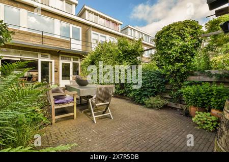 Diese einladende Terrasse im Hinterhof verfügt über komfortable Sitzgelegenheiten, einen modernen Esstisch und reichlich Grün, was eine ruhige urbane Oase perfekt für Familien schafft Stockfoto