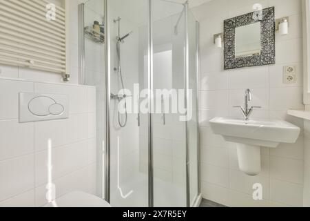 Ein elegantes, modernes Badezimmer mit Glasdusche, weißen Fliesen und Spiegel im Meester Rendorplaan 8 Stockfoto