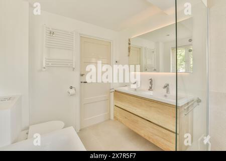 Ein helles und luftiges, modernes Badezimmer mit geräumiger Glasdusche, zwei Waschbecken und Holzwaschbecken im Molenveenweg Stockfoto
