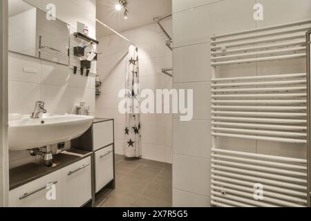 Ein modernes weißes Badezimmer mit Standwaschbecken, weißen Schränken und einem Duschvorhang mit Sternmuster Stockfoto