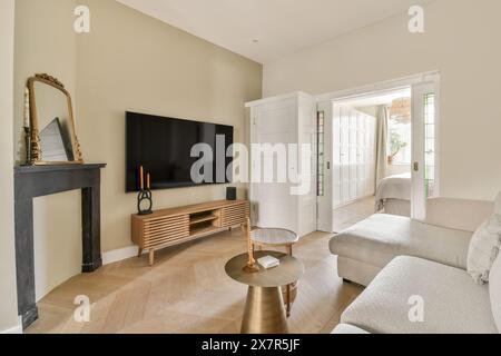 Dieses Bild zeigt ein stilvolles Wohnzimmer mit modernem Design. Es verfügt über natürlichen Holzfußboden, einen modernen Fernseher und geschmackvolle, weiche Möbel Stockfoto