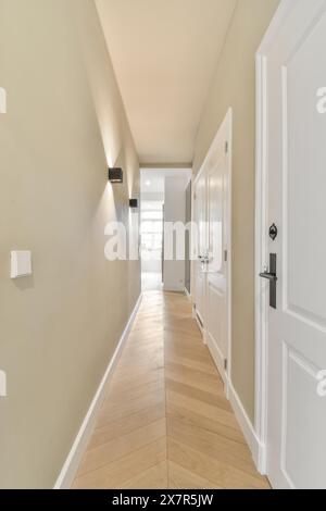 Ein moderner und gut beleuchteter Korridor mit Holzfußboden, weißen Türen und neutralen Wänden, perfekt für zeitgenössische Innenarchitektur Stockfoto