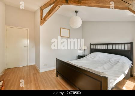 Ein gut beleuchtetes, minimalistisches Schlafzimmer mit Holzrahmen, freiliegenden Holzbalken und einfacher moderner Einrichtung. Stockfoto