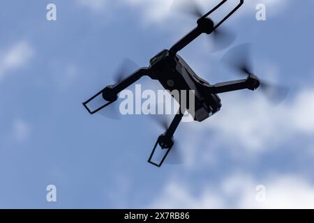 Drohne fliegt in der Luft in geringer Höhe gegen einen blauen Himmel. Drohne macht Fotos. Moderne neue Technologie. Fertiger Hintergrund mit Platz für Ihren Text. Stockfoto