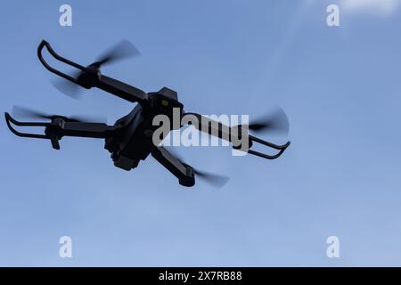 Drohne fliegt in der Luft in geringer Höhe gegen einen blauen Himmel. Drohne macht Fotos. Moderne neue Technologie. Fertiger Hintergrund mit Platz für Ihren Text. Stockfoto