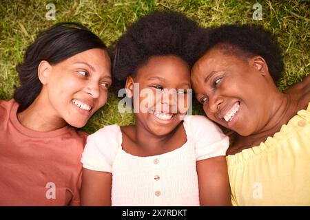 Blick Hinunter Auf Die Weibliche Familie Der Drei Generationen, Die Lacht Und Auf Dem Gras Liegt, Auf Dem Land Stockfoto