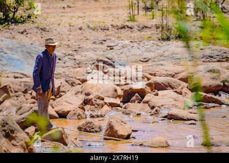 Antananarivo, Madagaskar 07. Oktober 2023. Ein älterer Mann fängt Fische für seine Tochter in einem kleinen Bach Stockfoto