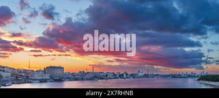 Malerische dramatische Wolken bei Sonnenuntergang über dem Stadtdamm und dem Fluss Dnieper. Stockfoto