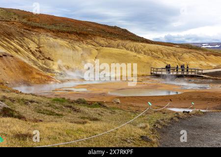 Krysuvik, Island, 14.05.22. Seltun geothermische Gegend in Krysuvik mit dampfenden heißen Quellen, gelben und orangen Schwefelhügeln und Touristen, die auf Wo stehen Stockfoto