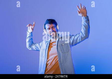 Glücklicher junger Mann, der nachts mit Kopfhörern zur Musik tanzt Stockfoto