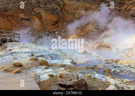 Landschaft des Seltun Geothermalgebietes in Krysuvik mit kochenden heißen Quellen, gelben und orangen Farben von Schwefelhügeln und touristischen Boardwalks, Island. Stockfoto