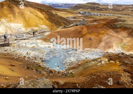 Seltun geothermische Gegend in Krysuvik mit dampfenden heißen Quellen, gelben und orangen Schwefelhügeln und Menschen, die auf den Stegen spazieren gehen. Stockfoto