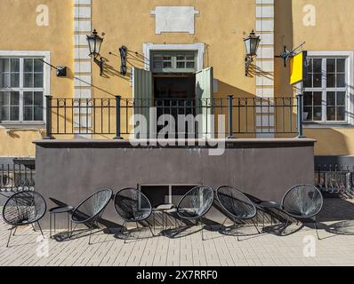 Korbstühle und kleine Tische in einem Straßencafé in der Altstadt von Riga, Lettland. Stockfoto