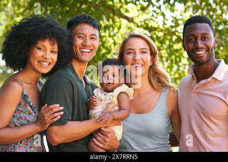 Porträt Von Multi-Racial Familie Und Freunden, Die Ihr Baby Draußen Auf Dem Land In Gruppe Zusammen Umarmen Stockfoto