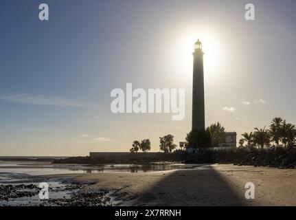 Faro de Maspalomas: Der Leuchtturm in Maspalomas, Insel Grand Canary bei Ebbe mit der Sonne hinter der Spitze des Leuchtturms. Stockfoto