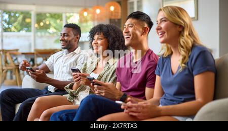 Eine Gruppe Aufgeregter Multi-Racial-Freunde, Die Auf Sofa Sitzen Und Gemeinsam Computerspiele Spielen Stockfoto