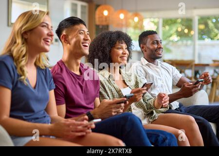 Eine Gruppe Aufgeregter Multi-Racial-Freunde, Die Auf Sofa Sitzen Und Gemeinsam Computerspiele Spielen Stockfoto