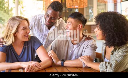 Gruppen Von Multi-Racial-Freunden, Die Zu Hause Am Tisch Sitzen, Lachen Und Miteinander Reden Stockfoto