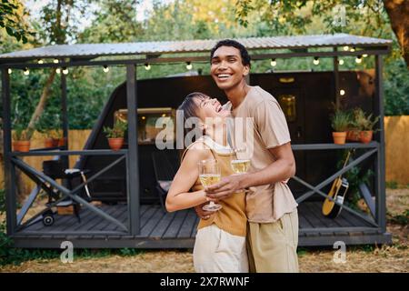 Ein Mann und eine Frau, ein interrassisches Paar, stehen Seite an Seite vor einem Wohnmobil, bereit für einen romantischen Kurzurlaub. Stockfoto