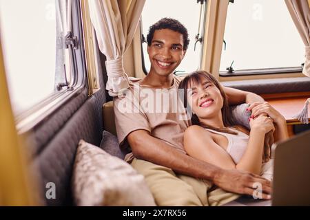 Ein Mann und eine Frau sitzen nebeneinander in einem Zug und blicken aus dem Fenster, während sie zusammen auf ein romantisches Abenteuer reisen. Stockfoto