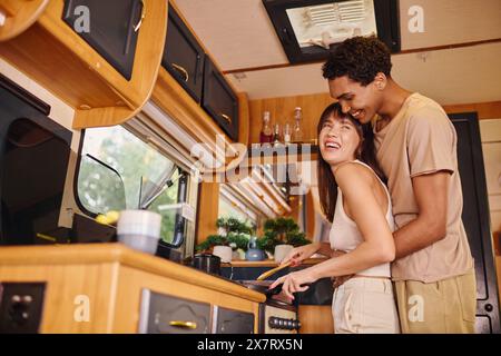 Ein Mann und eine Frau stehen zusammen in einer gemütlichen Küche und teilen einen Moment der Zweisamkeit, während sie eine Mahlzeit zubereiten. Stockfoto